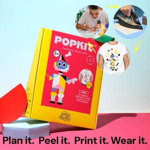 May include: A yellow POPKIT Fashion Print Kit box featuring a robot design. The kit includes a white t-shirt with a robot graphic, and instructions. The text on the box says "Plan it. Peel it. Print it. Wear it."
