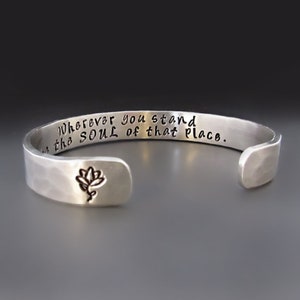 May include: Silver bracelet with a hammered finish and an engraved quote: "Wherever you stand, the SOUL of that place."