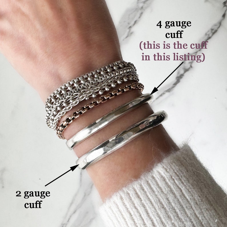 May include: A collection of silver-toned bracelets including three chain-link styles and two smooth metal cuffs. Text labels indicate a 4 gauge cuff and a 2 gauge cuff. The bracelets are stacked on a wrist, showcasing varying textures and thicknesses.