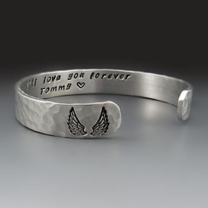 May include: Silver bracelet with a hammered finish and engraved with the words "I'll love you forever Tommy" and a heart. The bracelet has a pair of angel wings on the back.