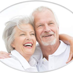 May include: An oval image shows an elderly couple smiling and embracing. The woman, with short, grey hair, wears a white collared shirt. The man, with grey hair and a beard, wears a white polo shirt. Both are smiling broadly, suggesting happiness.