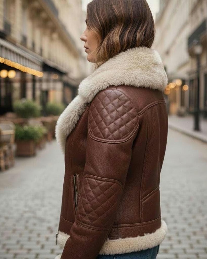 Puede incluir: Chaqueta de cuero marr&oacute;n con cuello y forro de borrego color crema. La chaqueta presenta parches acolchados en hombros y codos, cierre de cremallera y un estilo aviador cl&aacute;sico.