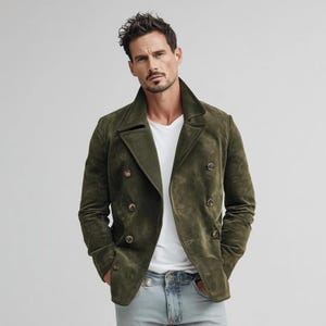 May include: Olive green suede double-breasted jacket with four gold-tone buttons. The jacket has a notched lapel and two front pockets. The model is wearing a white t-shirt and light blue jeans.