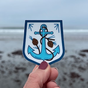May include: A blue anchor sticker with two pine cones on either side of the anchor. The sticker has a white background and the text "PATHFIND" at the bottom.