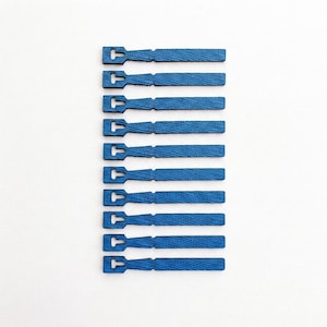 May include: A set of ten flat, blue, rectangular wooden pieces arranged in a vertical column. Each piece features a distinct T-shaped cutout at one end, with a visible wood grain texture throughout the surface of the blue-dyed material.