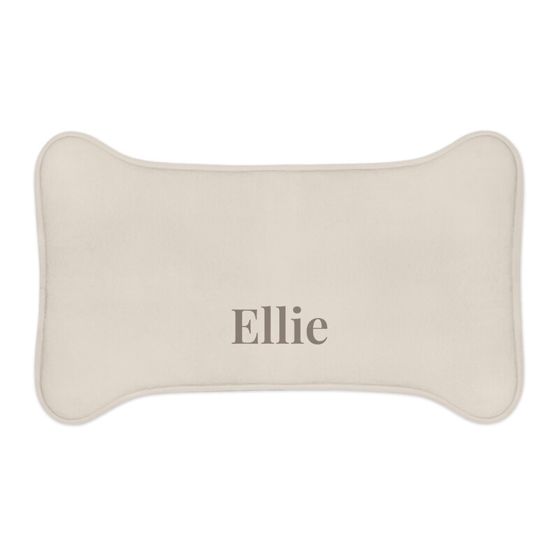 Peut inclure: Coussin pour chien en forme d'os, de couleur beige clair. Le nom "Ellie" est imprim&eacute; en gris. Ce coussin est con&ccedil;u pour le confort et le soutien des animaux de compagnie.