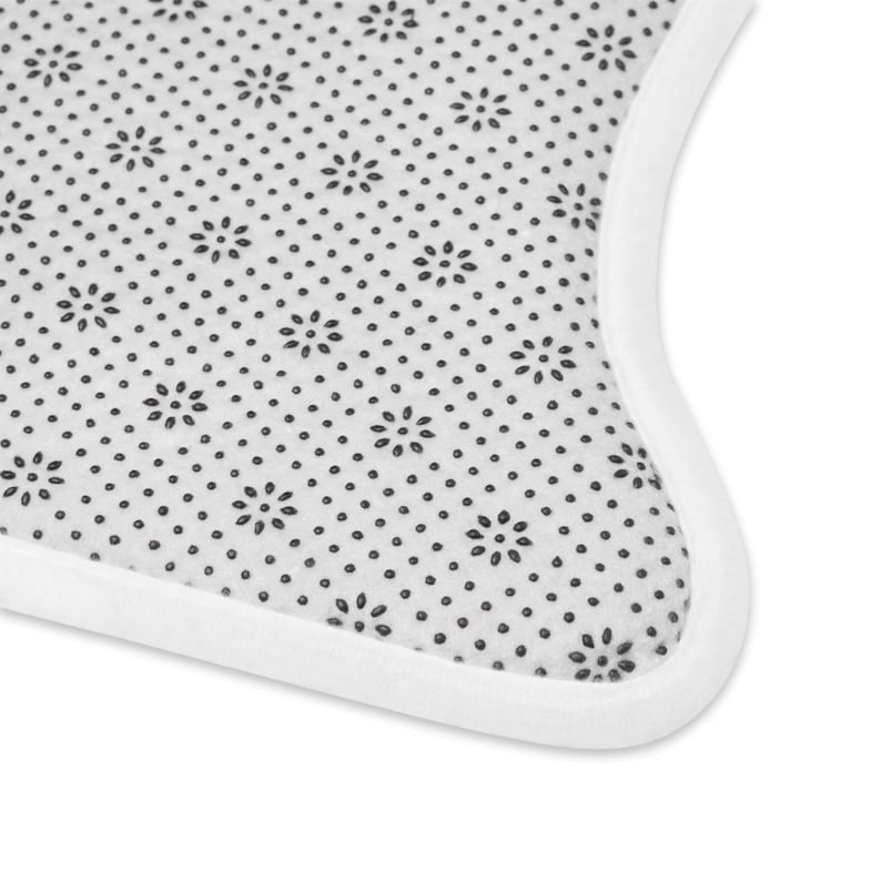 Peut inclure: Gros plan sur un tapis blanc avec un motif floral noir et une bordure blanche. La surface du tapis est recouverte de petits motifs de fleurs et de points noirs. La bordure est de couleur blanche unie.