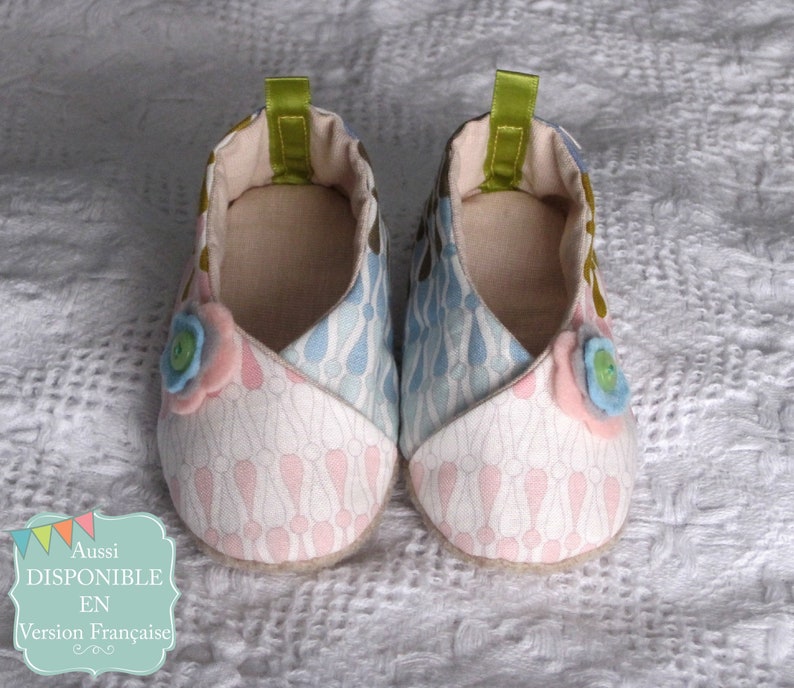 K&ouml;nnte beinhalten: Ein Paar Babyschuhe mit einem rosa-blauen Blumenmuster. Die Schuhe haben einen wei&szlig;en Hintergrund mit rosa-blauen Akzenten. Die Schuhe sind aus Stoff und f&uuml;hlen sich weich und bequem an.