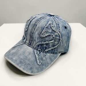 Boné de beisebol em jeans com estampa de borboleta desgastada, estilo grunge streetwear.