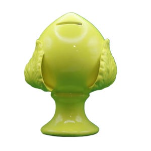 May include: A chartreuse-colored ceramic piggy bank shaped like a stylized flower or bud. The bank has a slot for coins on top and decorative leaf-like elements on the sides. The base is a flared pedestal.
