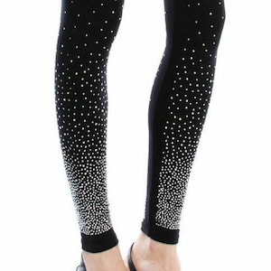 May include: Black leggings with a pattern of small, white, sparkling dots that fade towards the ankles. The leggings are worn with black high-heeled shoes.