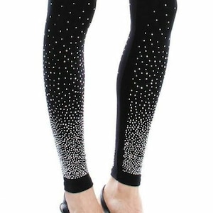 May include: Black leggings with a pattern of small, white, sparkling dots that fade towards the ankles. The leggings are worn with black high-heeled shoes.