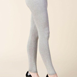 May include: Light gray leggings with a subtle sparkle design at the ankles. The leggings are paired with black platform high heels. The overall look is casual yet stylish, suitable for various occasions.