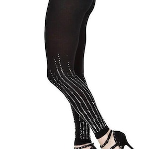 May include: Black leggings with a sparkling rhinestone design on the lower legs. The leggings are paired with black high-heeled shoes with multiple straps and studded accents. The overall look is stylish and elegant.
