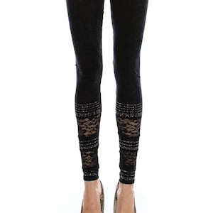 May include: Black leggings with lace and rhinestone accents. The leggings feature a high waist and are form-fitting. The lower leg has a lace panel with rhinestone embellishments. The website "VOCALAPPAREL.COM" is printed at the bottom.