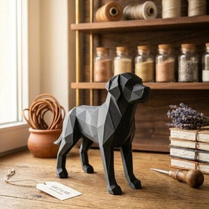 Könnte beinhalten: Eine schwarze, geometrische Hundeskulptur steht auf einer Holzoberfläche. Der Hund hat ein facettiertes Design und befindet sich neben einem Etikett mit der Aufschrift "GEO-LAB". Der Hintergrund umfasst ein Regal mit Gläsern und Garnrollen.