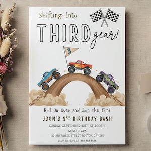 May include: A white invitation card with the text "Shifting Into THIRD gear!" and "Roll On Over and Join the fun!" features three monster trucks racing over a brown hill. The card is for JSON'S 3rd birthday.