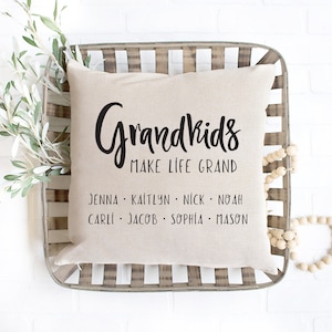May include: A beige throw pillow with black text that reads "Grandkids Make Life Grand" and lists the names Jenna, Kaitlyn, Nick, Noah, Carli, Jacob, Sophia, and Mason.
