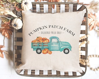 May include: A beige pillow with a blue truck carrying pumpkins and the text "Pumpkin Patch Farm - Delivered Fresh Daily -" printed on it.