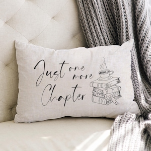 May include: White throw pillow with black text that reads "Just one more chapter" and a black and white illustration of a stack of books with a cup of coffee on top.