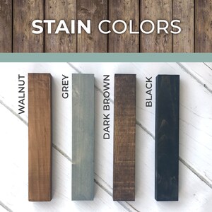 Puede incluir: Cuatro muestras de madera te&ntilde;idas en diferentes colores: nogal, gris, marr&oacute;n oscuro y negro. Las muestras de madera est&aacute;n dispuestas verticalmente sobre un fondo de madera blanco. El texto "STAIN COLORS" est&aacute; en la parte superior de la imagen.