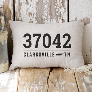 May include: A white throw pillow with black text that reads "37042 Clarksville TN" and a small black outline of the state of Tennessee.