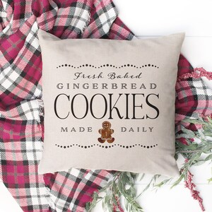 May include: A beige throw pillow with the text "Fresh Baked Gingerbread Cookies Made Daily" and a gingerbread man graphic.