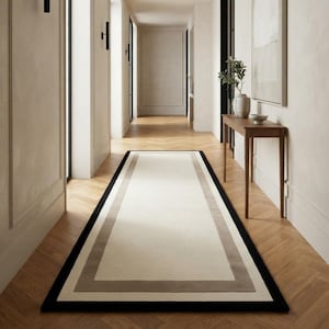 May include: A rectangular runner rug featuring a large cream-coloured centre panel, a wide light grey border, and a thin black outer edge. The rug is positioned lengthwise on a light brown wooden floor with a herringbone pattern in a hallway.