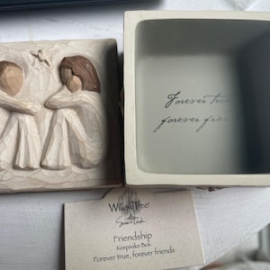 Könnte beinhalten: Beige Andenkenbox mit Deckel mit zwei geschnitzten Figuren, die sich umarmen. Im Inneren der Box steht in Schriftform "Forever true, forever friends". Eine Karte trägt die Aufschrift "Friendship Keepsake Box".