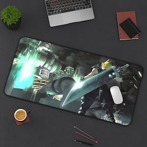 Może przedstawiać: Czarna prostokątna podkładka pod mysz z sceną z Final Fantasy VII z postacią trzymającą duży miecz. Podkładka ma czarną obwódkę i jest otoczona laptopem, myszką, ołówkami i filiżanką kawy.