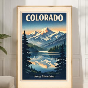 May include: A framed art print featuring a vintage-style illustration of the Colorado Rocky Mountains. The artwork depicts snow-capped peaks, a serene lake reflecting the mountains, and the text "COLORADO - Rocky Mountains" in a classic font.