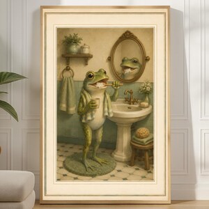 Könnte beinhalten: Gerahmter Kunstdruck, der einen Frosch beim Zähneputzen in einem Badezimmer zeigt. Der Frosch steht auf einer grünen Matte, trägt ein Handtuch und blickt in einen Spiegel. Das Badezimmer hat ein Waschbecken, einen Handtuchhalter und einen kleinen Hocker.
