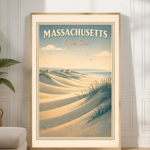 Op de afbeelding: Een ingelijste vintage reisposter voor Massachusetts, Cape Cod. Het kunstwerk toont zandduinen, oceaan en lucht in een retrostijl. De poster zit in een houten lijst en wordt getoond in een kamer met een plant en decoratieve vazen.