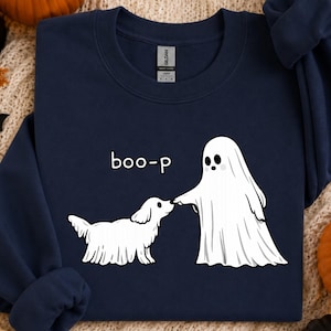 May include: A navy blue crewneck sweatshirt featuring a white graphic of a ghost touching the nose of a small dog. The text "boo-p" is printed in white above the dog. The garment has a standard ribbed collar and long sleeves with ribbed cuffs.