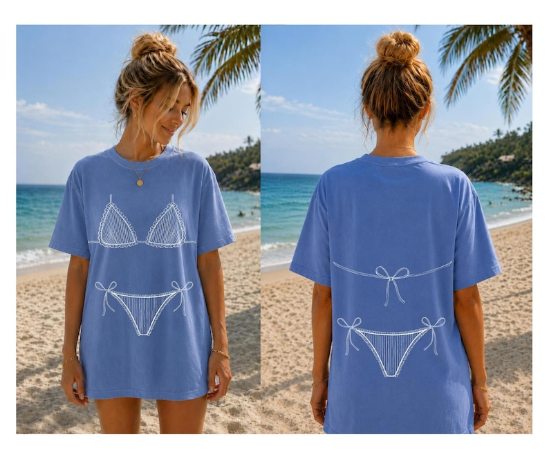 May include: A periwinkle blue short-sleeve t-shirt featuring a white line-art graphic of a bikini on the front and the back. The front displays the bikini top and bottom, while the back shows the bikini bottom and the tie strings of the top.