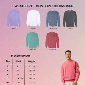 May include: Comfort Colors 1566 sweatshirts in violet, white, blue jean, pepper, seafoam, and crimson. A measurement chart lists sizes S through 2XL with width and length in inches. A person wears a crimson sweatshirt to show the fit and style.