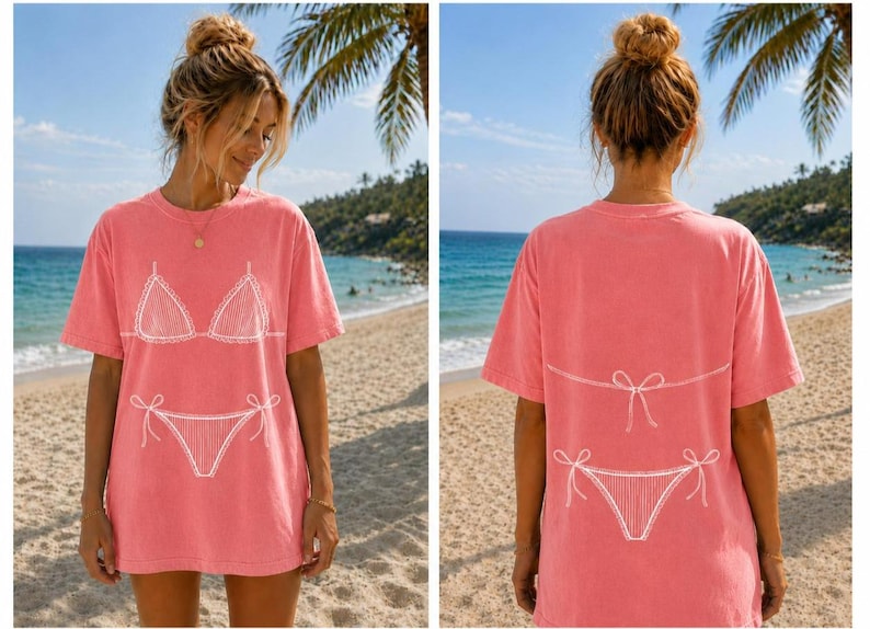 May include: A coral pink short-sleeve t-shirt featuring a white line art graphic of a bikini top on the front and a bikini bottom with a tie-side detail on the back. The shirt has a crew neckline and a relaxed, loose-fitting silhouette.