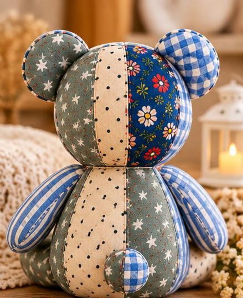May include: A patchwork teddy bear constructed from various fabric patterns including blue and white gingham, sage green with white stars, cream with black polka dots, and a dark blue floral print with red and white daisies, featuring round ears.