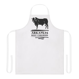 May include: White apron with a black bull silhouette and the text "ARKANSAS BEEF FARMERS". The apron has a neck loop and waist ties. Ideal for cooking and grilling, this apron is a practical kitchen accessory.