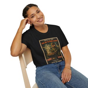 Puede incluir: Camiseta negra con un gráfico retro de una criatura asando comida, con el texto "TAKE ME TO YOUR LEADER" y "AFTER THE COOKOUT". El diseño tiene una estética de documento clasificado vintage.