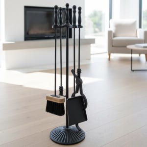 Può includere: Un set di attrezzi per camino neri con supporto. Il set include un attizzatoio, una paletta, una spazzola e delle pinze. Gli attrezzi hanno manici decorativi e sono esposti su una base rotonda e scanalata. La spazzola ha un manico in legno e setole nere.