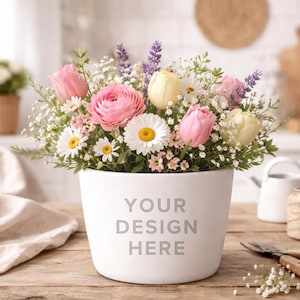 May include: A white ceramic flower pot filled with a vibrant arrangement of pink roses, yellow tulips, white daisies, and purple lavender. The pot has the text "YOUR DESIGN HERE" printed on the front. The arrangement sits on a wooden surface.