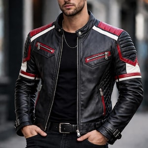 May include: Black leather jacket with red and white accents. The jacket features a quilted design on the shoulders and sleeves, with zippered pockets and a front zipper closure. The jacket is worn with a black shirt and dark jeans.