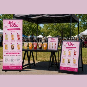 Könnte beinhalten: Ein schwarzes Faltpavillon-Setup für einen Dirty Soda-Stand mit einem hohen rosa Banner, einer kleinen gerahmten Speisekarte und einem rosa Aufsteller. Sechs durchsichtige Plastikbecher mit bunten Limonaden stehen auf einem schwarzen Tisch.