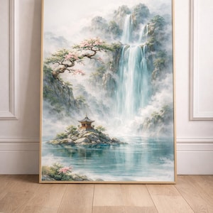 Könnte beinhalten: Gerahmtes Landschaftsgemälde, das einen ruhigen Wasserfall zeigt, der in einen See stürzt. Auf einer felsigen Insel befindet sich eine kleine Pagode mit einem Baum mit rosa Blüten. Das Kunstwerk ist in einem goldfarbenen Rahmen gerahmt.