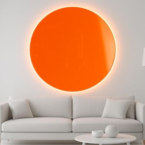May include: A contemporary living room featuring a large, orange, circular artwork on the wall. Beneath it is a white sofa with cushions, a white coffee table, and a white floor lamp. The room has a minimalist design.