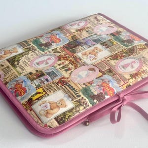 Può includere: Un astuccio rettangolare trapuntato con bordo rosa e fiocco abbinato. La custodia presenta un collage di illustrazioni in stile vintage, tra cui orsacchiotti, bambini e ritagli di giornale. La combinazione di colori generale è morbida e pastello.