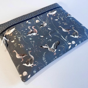 Op de afbeelding: Een rechthoekige, donkergrijze stoffen etui met ritssluiting. De etui is versierd met een patroon van ganzen, planten en bloemen in grijstinten, bruin en wit. De ritssluiting heeft een kleine kwast bevestigd.