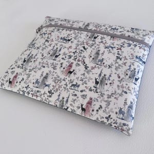May include: A square, zippered pouch with a whimsical forest print. The fabric features deer, figures in flowing gowns, and floral elements in shades of gray, pink, and blue on a white background. The zipper is gray.