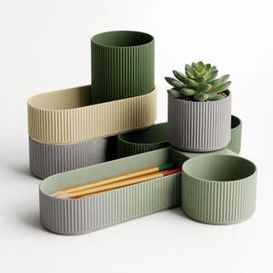 May include: A modular desk organizer set featuring ribbed cylindrical and oval containers in shades of olive green, light beige, and gray. The set includes a small pot holding a green succulent plant and a tray containing two yellow pencils.